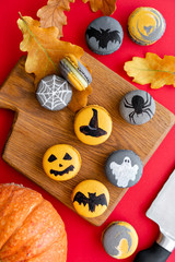 Halloween scary cookies with pumpkin on wooden cut board. pattern Bat , patina, ghosts and spiders. Red color background, top view