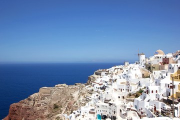 Romantic view of beautiful white washed buildings against blue sky, clouds and vivid sea in Santorini island, Oia, Greece