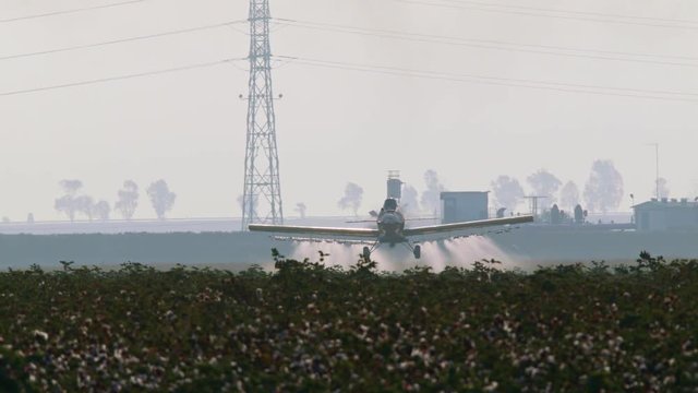Crop duster spraying chemicals over a cotton field - slow motion