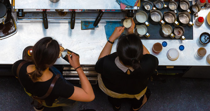 Unrecognisable Female Baristas Making Coffee At Coffee Machine In Shop. Top Aerial View