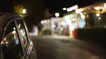 Out of focus backdrop of building with bright lights and car in foreground