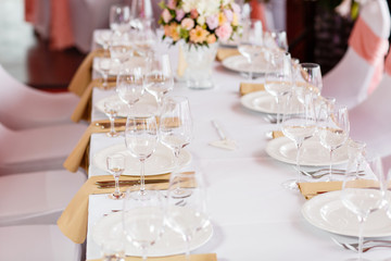 Table at a luxury wedding reception. Beautiful flowers on the table. Serving dishes, glass glasses, waiters work,