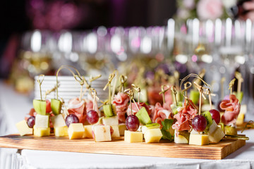 the buffet at the reception. Glasses of wine and champagne. Assortment of canapes on wooden board....
