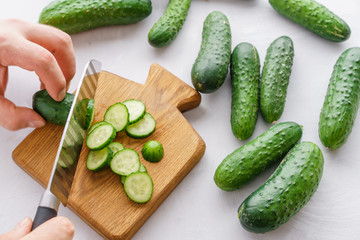 Mans hands cutting cucumbers for detox water. Top view. Process of preparing energy cocktail