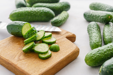 Cutting board with sliced cucumbers for detox water. Process of preparing energy cocktail