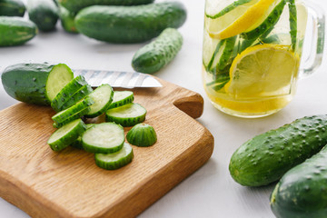Cutting board with sliced cucumbers for detox water. Process of preparing energy cocktail