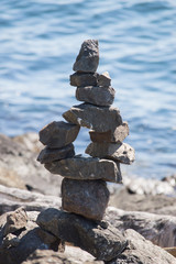 A balanced tower of rocks stacked in front of the water.