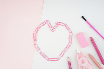 Creative arrangement of stationery such as pencils and brushes on a pastel colored paper. Feminine themed colors like soft red and pink. Flat lay view.