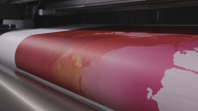 Industrial Big Printer, professional press, and paper supply. Robotized workflow, detailed shot of the passing print head, while processing large, vinyl, glossy, rolls. Color samples before final ok.