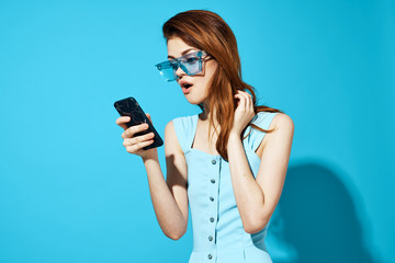 surprised woman in glasses with a smartphone on a blue background