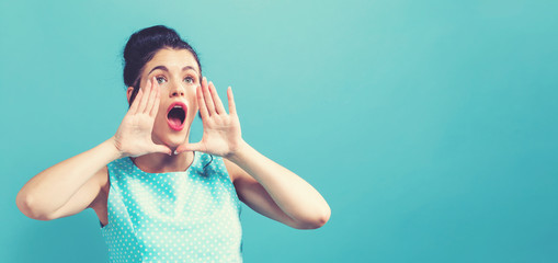 Young woman shouting on a solid background
