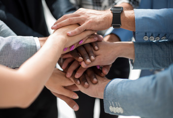 group of people in the office folded their hands together