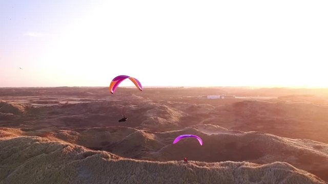 Drone/Aerial shot of a parapenter flying over the duns ot the Netherlands. Shot was made by a professional drone pilot.