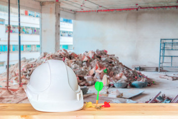 helmet plastic white with three dart. hat safety equipment working of engineering concept on wood floor table with copy space. blur garbage construction site building background