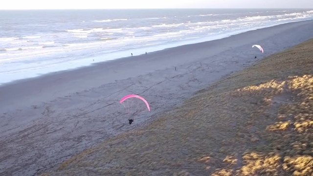 Drone/Aerial shot of a parapenter flying over the duns ot the Netherlands. Shot was made by a professional drone pilot.