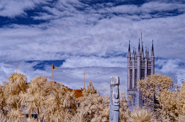Turrents of a fort tower behind red foliage against a backdrop of cloudy blue skies