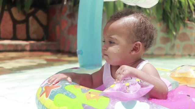 A close shot of a baby having fun in a flotation device in a children's pool.