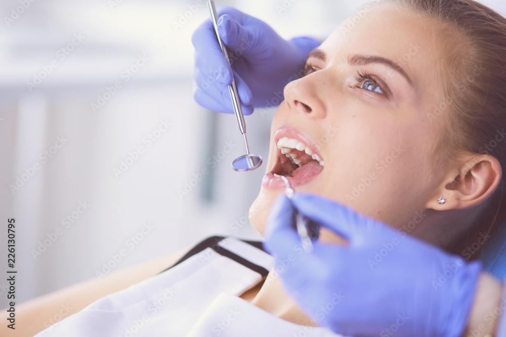 Wall mural young female patient with open mouth examining dental inspection at dentist office.