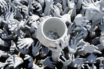 Many Poor hungry human hands sculpture around money bowl at Wat Rong Khun Temple, Chiang Rai city, Thailand