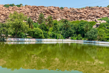 Fototapeta na wymiar Sacred pond associated with Ramayana against a backdrop of boulders in Hampi, India