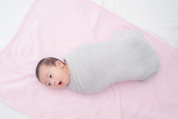 4 weeks old newborn baby wrapped in grey blanket