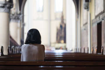 Rear view of devout woman praying in the church