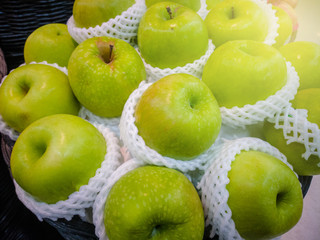 Green apple is placed on a basket for sale in a supermarket