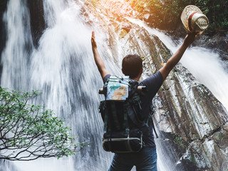 Obraz premium male hiker with raised hands and waterfall background