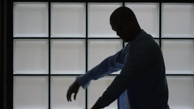 Silhouette of man putting his shirt on in the morning