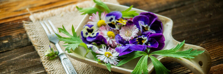 Sunflower sprouts, cucumber and edible flowers salad on wooden bowl