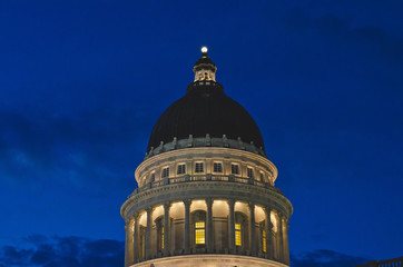 The top of the utah state capitol dome in the night lights under the dark sky. 