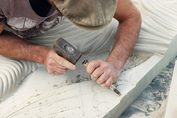 A sculptor is working on a white stone