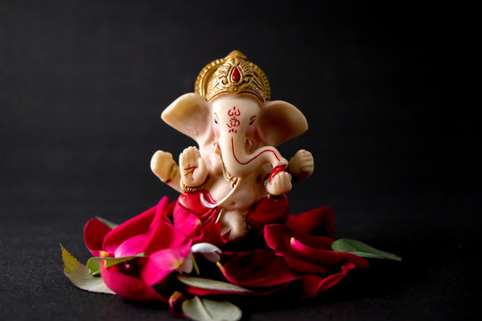 Lord Ganesha Idol with rose petals, white flowers and leaves on Black  background, Ganesh pooja Stock Photo | Adobe Stock
