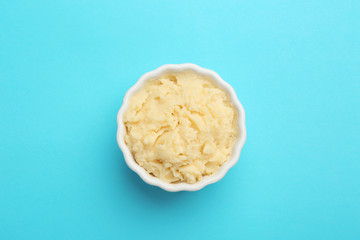 Bowl with tasty mashed potatoes on color background, top view