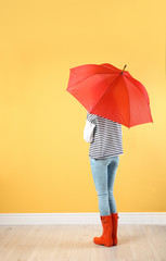 Woman with red umbrella near color wall