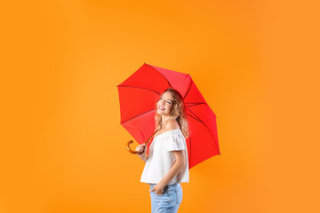 Woman with red umbrella on color background
