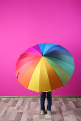Little boy with rainbow umbrella near color wall