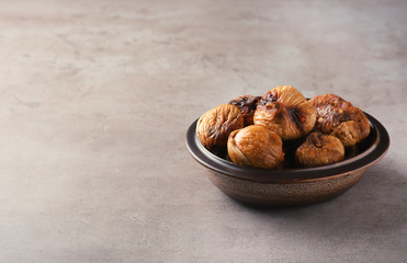 Bowl with dried figs on grey background. Space for text