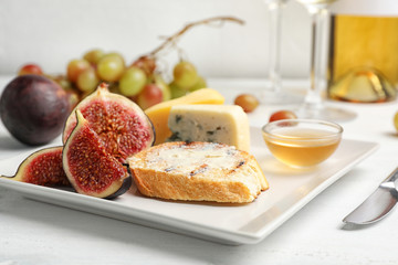 Ripe figs and slice of bread with butter on plate