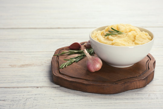 Bowl with mashed potatoes on wooden board. Space for text
