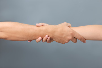 People holding hands together on gray background, closeup. Concept of support and help