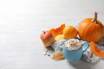 Cup with pumpkin spice latte, autumn decor and space for text on light table