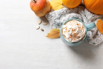 Fototapeta premium Flat lay composition with cup of pumpkin spice latte, autumn decor and space for text on light table