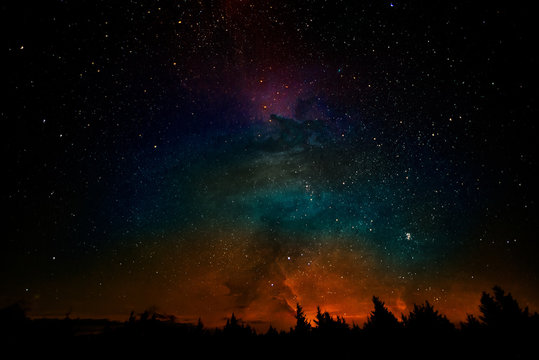 Milky way and fantasy galaxy clouds above the forest landscape, collage. The elements of this image furnished by NASA.