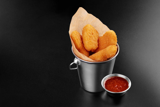 BBQ fried chicken naggets in a metal bucket onblack background with sauce food m