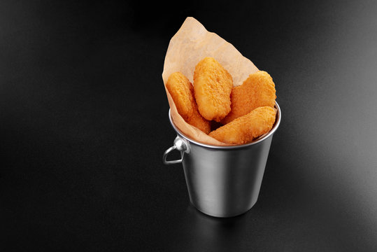 BBQ fried chicken naggets in a metal bucket onblack background with sauce food m