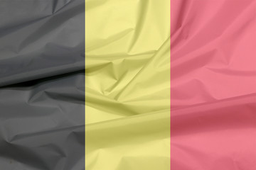 Fabric flag of Belgium. Crease of Belgian flag background, it is a vertical tricolor of black, yellow, and red.