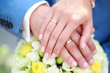 hands of the newlyweds on the wedding bouquet