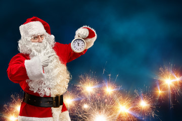 Santa Claus on a blue background points his finger at the clock. Christmas concept. © k_e_n