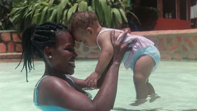 An African women and her baby daughter playing together lovingly in a swimming pool.